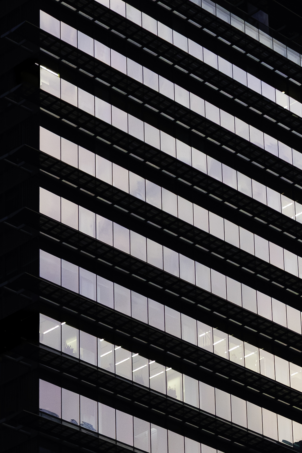 Glass-curtain-wall office tower at night, lit from within, geometric grid